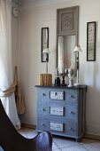 Dull mirrors above battered chest of drawers