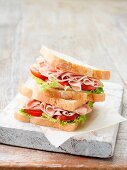 Stapel von Schinken-Sandwiches mit Blattsalat und Tomaten