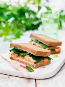 A black bread sandwich with salmon, spring onions, radishes and spinach