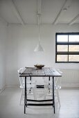 White-painted chars around wooden table on metal trestles in simple dining area