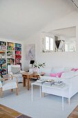 Delicate side table, white sofa, round wooden table and opening in internal wall in modern living area