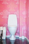 Toilette vor rosa Tapetenwand mit floralem Muster