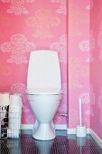 Toilet against pink wallpaper with floral pattern