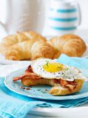A croissant with bacon and a fried egg