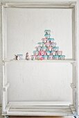Advent calender hand-made from decorated tin cans in white-painted wooden frame
