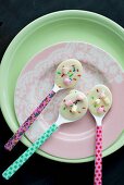 Colourful spoons covered with white chocolate and bright hundreds and thousands