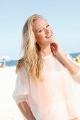 A blonde woman on the beach wearing a see-through woollen jumper