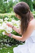 Young woman looking at white roses in garden