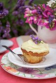 An almond cupcake with lavender cream on a summer table outside
