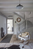 Fur blanket on rocking chair at foot of grey staircase in restored hallway