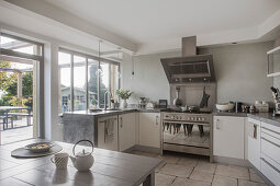 White, U-shaped kitchen counter with concrete worksurface and view of terrace