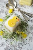 A petit four decorated with a chick, thyme and sugar eggs