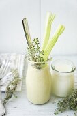 A banana and avocado smoothie garnished with celery sticks and thyme