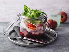 A layered soused herring with beetroot in a jar