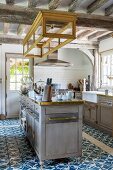Island counter and ornate blue and white floor tiles in country-house kitchen