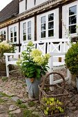 White garden bench, basket of apples and hydrangeas in zinc bucket outside country house with white windows