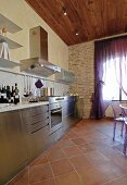 Modern stainless steel kitchen with terracotta floor tiles