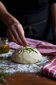 Bread dough being sprinkled with rosemary