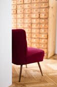 Red retro easy chair in hallway with apothecary cabinet against far wall
