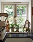 Ausschnitt einer Küchenzeile mit Spülbecken vor Fenster, seitlich Vintage Küchenwaage