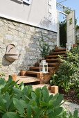 Garden sink on stone outside wall of renovated country house and white lanterns on treads of cedar-wood steps