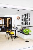 White lacquered built-in bench under photo gallery in elegant black and white living area with yellow color accent and passage