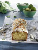Lime and coconut cake, sliced, on a piece of paper on a blue wooden table