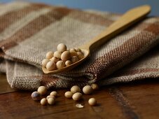 Soya beans on a wooden spoon on a jute cloth