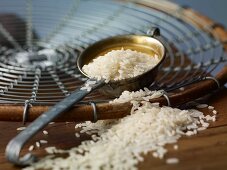 Rice in a ladle and on a wooden table
