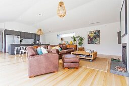 Open living area with leather sofa and fireplace, in the background dining area and fitted kitchen