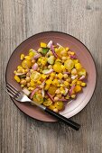 A yellow vegetable salad with tomatoes, sweetcorn, peppers and chickpeas