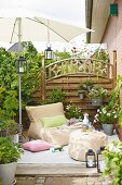 A beanbag-style armchair and an upholstered stool under a parasol on a terrace