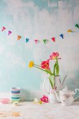 Colourful bunting and a bunch of flowers in a vintage coffee jug