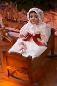 Old-fashioned Christmas toys: antique doll wearing nightcap in doll's bed
