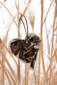 Heart-shaped pastry cutter filled with fat and sunflower seeds in wintry garden