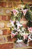 DIY Advent calender with numbered, decorated paper cones on green wreath on brick wall