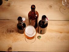 A glass of beer and three opened beer bottles