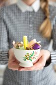 Woman holding vintage-style bowl of old sewing utensils