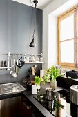 Dark kitchen with grey wall and utensils hung from wall-ounted bar