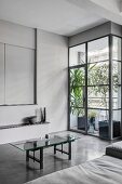 Coffee table with glass top on concrete floor in industrial loft apartment in shades of grey