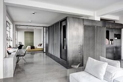 Concrete floor, cubic installation and bedroom in background in industrial loft apartment in shades of grey