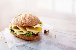 A rye bread roll with cheese and lettuce