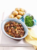 Beef and mushroom ragout from the oven with jacket potatoes and peas