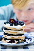 A stack of pancakes with blueberries and pansies
