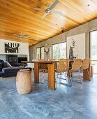 Open living with a solid table, modern wicker chairs, wooden ceiling and pictures