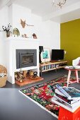 Farbenfrohes Wohnzimmer mit gelber Wand und buntem Teppich