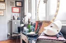 White mask in foreground and flea-market finds on table in front of window