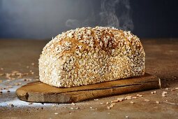 A steaming loaf of chia-spelt bread on a chopping board