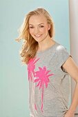 A young blonde woman wearing a grey T-shirt with pink sequinned palm trees