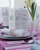 Pictures on menu cards and linen napkins with elegant napkin rings on festively set table